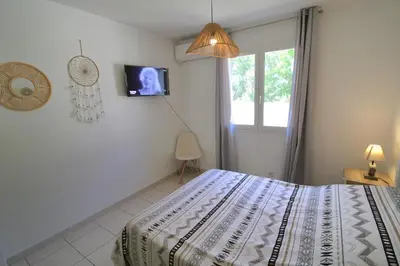 a bedroom with a bed and a tv on the wall at Villa l'Oranger in Sigean