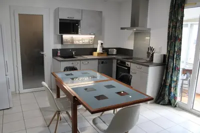 a kitchen with a wooden table and chairs in it at Villa l'Oranger in Sigean