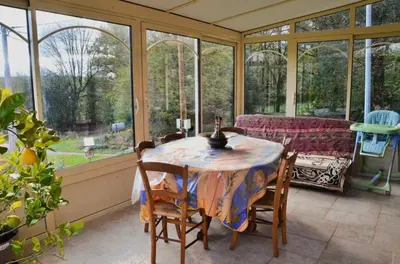 a conservatory with a table and chairs and windows at Violette in Saint-Pierre-de-Trivisy