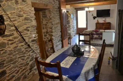 a dining room with a table and a stone wall at Violette in Saint-Pierre-de-Trivisy