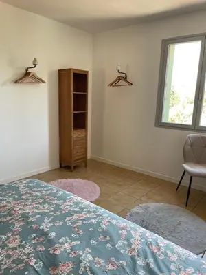 a bedroom with a bed and a window and a chair at Le Plô in Couffoulens