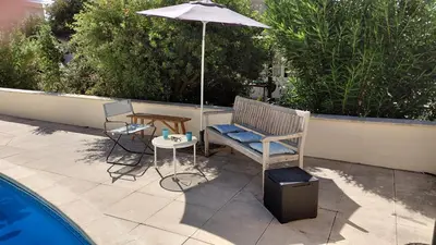 a patio with a bench and an umbrella next to a pool at Gite Mimosa in South of France - Entire Holiday Home in Sainte-Vallière