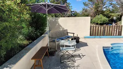 a patio with a bench and an umbrella next to a pool at Gite Mimosa in South of France - Entire Holiday Home in Sainte-Vallière