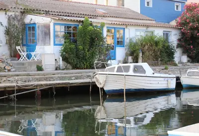 a boat docked at a dock next to a house at Authentic fisherman's house Maison de pêcheur authentique in Port-la-Nouvelle