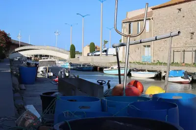 a marina with blue bins and boats in the water at Authentic fisherman's house Maison de pêcheur authentique in Port-la-Nouvelle