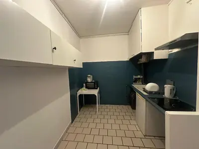 a small kitchen with white cabinets and a table at Appartement de type 3 de 65 m2 Narbonne centre in Narbonne