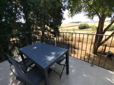 a blue table and chairs on a balcony with a fence at Les Tournesols gîte en pleine nature in Hounoux