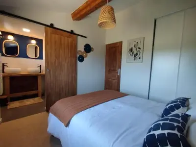 a bedroom with a bed and a bathroom with a sink at Les Tournesols gîte en pleine nature in Hounoux