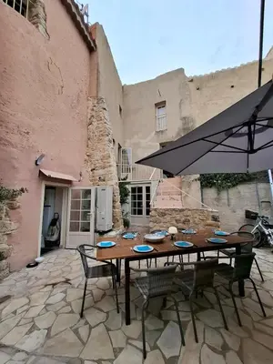 a wooden table with chairs and an umbrella on a patio at La Casita Sigean in Sigean
