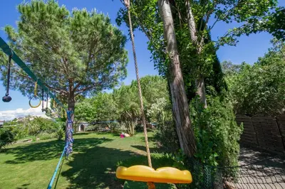 a swing in a park with a tree at villa la combe blanche - toboggan aquatique privée in Pépieux