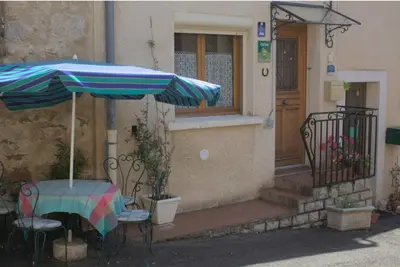 a table and chairs with an umbrella in front of a house at Gîte du Four à Chaux in Quillan