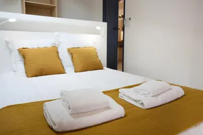 a white bed with two towels on top of it at Confort & espace avec climatisation - T4 central in Villefranche-de-Lauragais