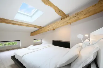 a bedroom with a white bed and wooden ceilings at Confort & espace avec climatisation - T4 central in Villefranche-de-Lauragais