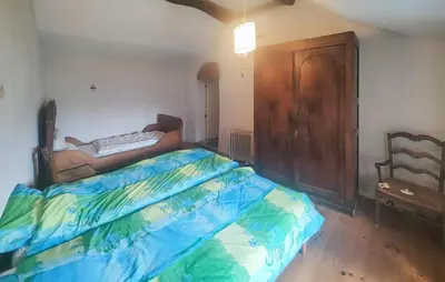 a bedroom with a bed and a wooden cabinet at Grande Maison De Village in Saint-Vincent