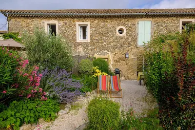 a stone house with two chairs in a garden at Domaine de Puychêne in Saint-Nazaire-dʼAude