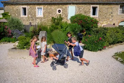 a group of children playing with a stroller in a garden at Domaine de Puychêne in Saint-Nazaire-dʼAude