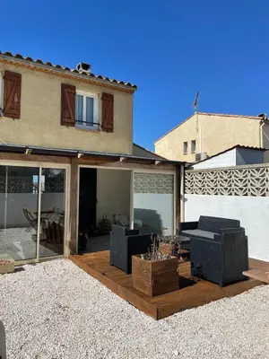 a living room with sliding glass doors in front of a house at Maison Gruissan proche du village et de la plage in Gruissan