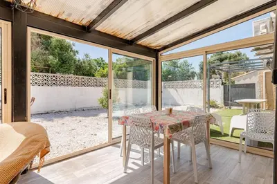 a glass house with a table and chairs on a patio at Maison Gruissan proche du village et de la plage in Gruissan
