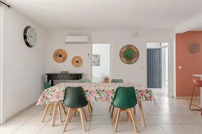 a dining room with a table and green chairs at Maison Gruissan proche du village et de la plage in Gruissan