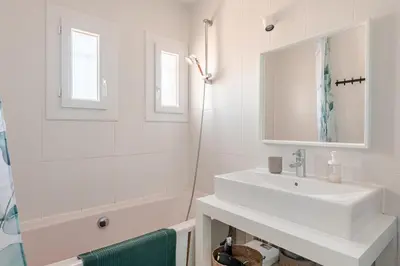 a white bathroom with a sink and a shower at Maison Gruissan proche du village et de la plage in Gruissan