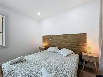 a bedroom with a large bed with a wooden headboard at Lakanaille - Appartement proche du centre - Wifi et Climatisation in Narbonne