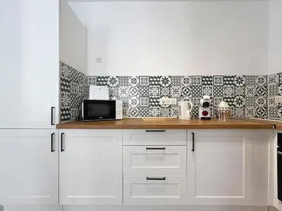 a kitchen with white cabinets and a black and white wallpaper at Le Patio - Grande Terrasse - Wifi et Climatisation in Narbonne