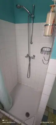 a shower in a white tiled bathroom at jolie appartement en rez de chaussée in Quillan