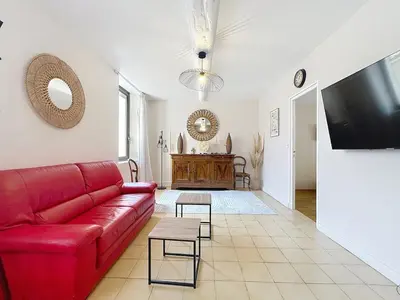 a living room with a red couch and a flat screen tv at Le Luxembourg - Appartement proche des Halles - Wifi in Narbonne