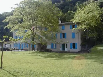 a house with blue windows in a field with trees at Auberge de jeunesse La Forge in Quillan