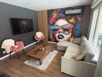 a living room with a couch and a large painting at Maison 95m2 6 personnes piscine in Narbonne