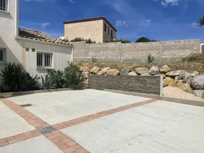 a driveway in front of a house with a retaining wall at Maison 95m2 6 personnes piscine in Narbonne