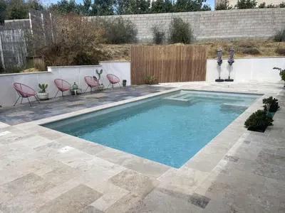 a swimming pool in a yard with chairs and a fence at Maison 95m2 6 personnes piscine in Narbonne