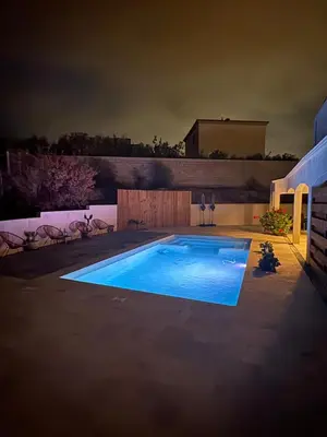 a large swimming pool in a backyard at night at Maison 95m2 6 personnes piscine in Narbonne