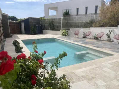 a swimming pool in a yard with chairs and flowers at Maison 95m2 6 personnes piscine in Narbonne