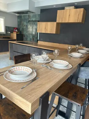 a wooden table with plates and wine glasses on it at Maison 95m2 6 personnes piscine in Narbonne