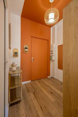 a hallway with an orange door and wooden floors at Le Sirocco - Studio Confort Lit Queen Size in Mazamet