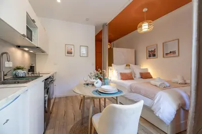 a bedroom with a bed and a table and a kitchen at Le Sirocco - Studio Confort Lit Queen Size in Mazamet