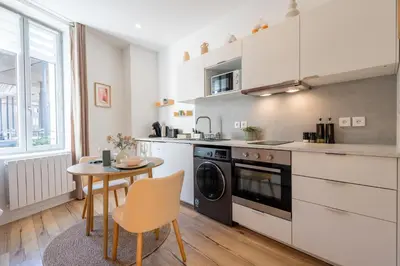 a kitchen with a table and a stove and a dishwasher at Le Sirocco - Studio Confort Lit Queen Size in Mazamet