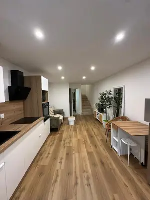 a kitchen and living room with a wooden floor at Petite maison cosy rénovée, entre mer et vignobles in Ouveillan