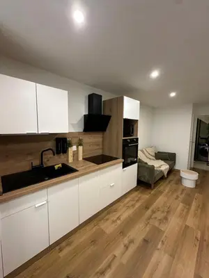 a kitchen with white cabinets and a living room at Petite maison cosy rénovée, entre mer et vignobles in Ouveillan