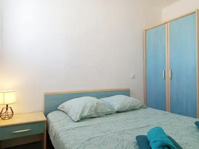 a bedroom with a bed and a blue cabinet at La Vie en Rose Cosy Proche du Port in Gruissan