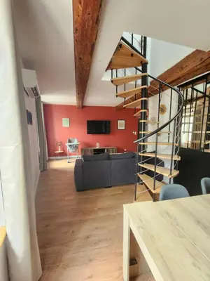 a living room with a spiral staircase in a loft at T3 Duplex with bike garage close in Castelnaudary