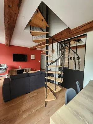 a spiral staircase in a living room with a couch at T3 Duplex with bike garage close in Castelnaudary