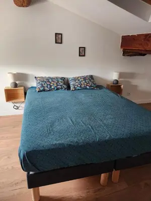 a bedroom with a bed with a blue comforter at T3 Duplex with bike garage close in Castelnaudary