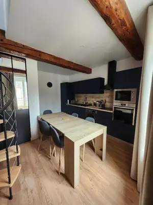 a kitchen and dining room with a wooden table and chairs at T3 Duplex with bike garage close in Castelnaudary