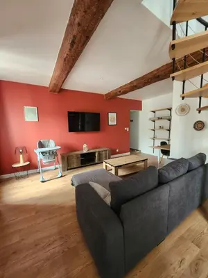 a living room with a gray couch and a red wall at T3 Duplex with bike garage close in Castelnaudary