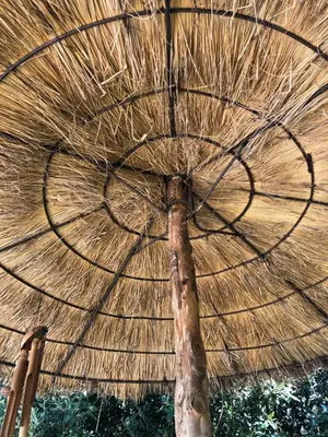 a large straw umbrella with a pole in front of it at La Bastide De Negra in Montesquieu-Lauragais