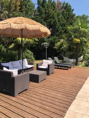 a wooden deck with chairs and an umbrella at La Bastide De Negra in Montesquieu-Lauragais