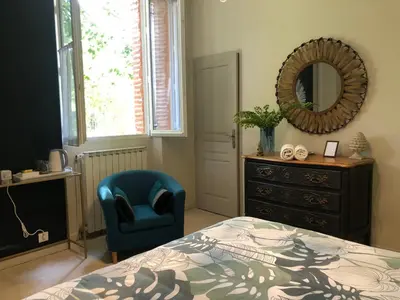a bedroom with a bed and a chair and a mirror at La Bastide De Negra in Montesquieu-Lauragais