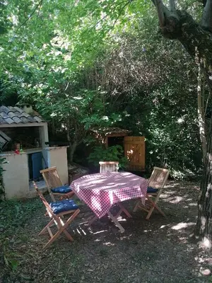 a picnic table and chairs in the shade of a tree at Proche Carcassone chambre avec salle de bain et WC privée Piscine salon et kitchenette partagés avec voyageurs in Cépie